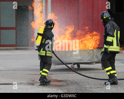 Due vigili del fuoco con bombole ossigeno spegnere il fuoco durante un esercizio in Firehouse Foto Stock