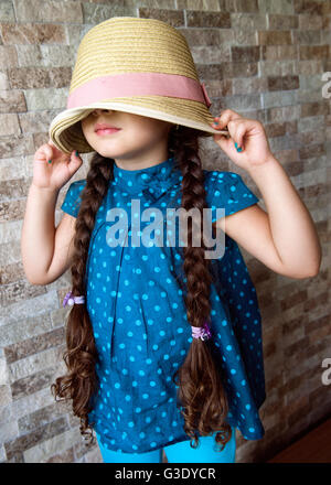 Bambina che ricopre la faccia con un cappello Foto Stock