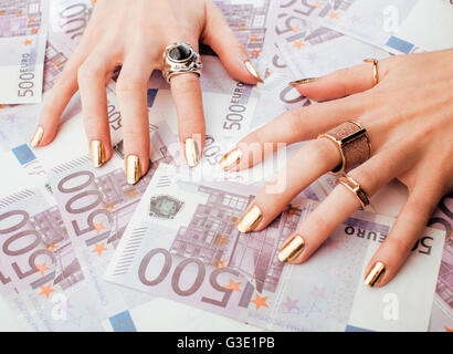 Le mani della donna ricca con golden manicure e molti gioielli anelli sul cash euro vicino fino a cinquecento Foto Stock