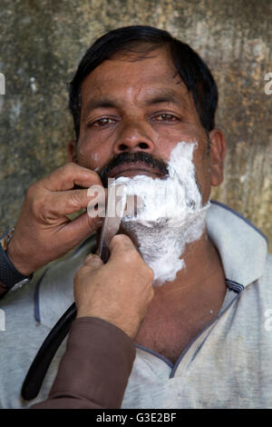 MUMBAI, India - 10 ottobre 2015: l'uomo non identificato da radere al barbiere di Mumbai, in India. Si tratta di una tradizione locale. Foto Stock