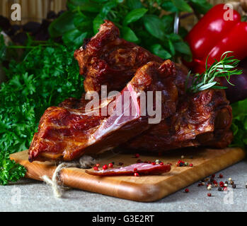 Carne affumicata , verdure e verdi su un tavolo da cucina Foto Stock