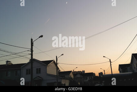 Due caccia militari volare sullo sfondo della luna crescent. condensa sentiero illuminato raggi del sole al tramonto. paese vil Foto Stock