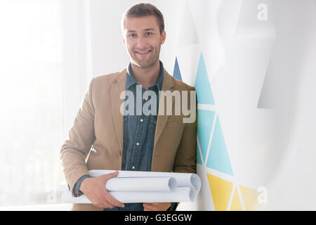 Ritratto fiducioso architetto azienda blueprints Foto Stock