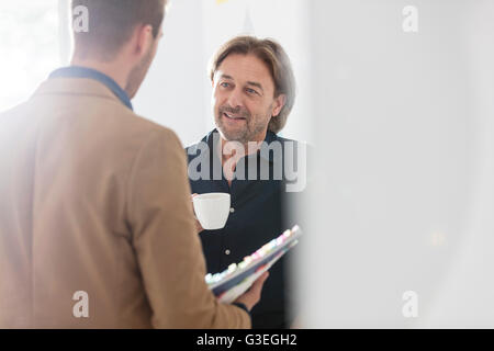 Gli imprenditori creativi di bere il caffè e a parlare in ufficio Foto Stock