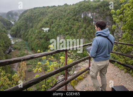 L uomo è il funzionamento del drone con un cascate di plitvice sfondo Foto Stock