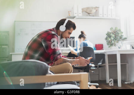 Giovane uomo con le cuffie utilizzando digitale compressa in appartamento Foto Stock