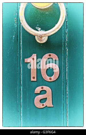 Luce blu periodo inglese in legno porta anteriore ornato di porta di ferro respingente. Numero civico posizione sotto la porta respingente. Soft di natura Foto Stock