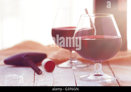 Due bicchieri di vino rosso su bianco tavola di legno, la luce del tramonto. Svuotare lo spazio di copia per l'editor di testo. Foto Stock