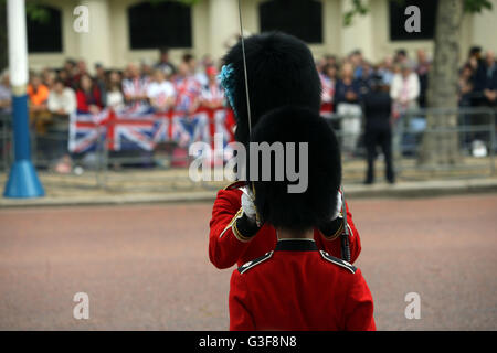 Un bearskin viene regolata prima che la royal cammino processionale verso il basso il Mall da Buckingham Palace e il centro di Londra per la sfilata delle Guardie a Cavallo per il Trooping la cerimonia di colore come la regina festeggia il suo compleanno ufficiale di oggi. Foto Stock