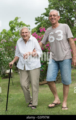 L'uomo aiutando felice senior lady passeggiate nel giardino Foto Stock