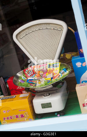 Vecchio vintage di strumenti di pesatura e di dolci per i bambini in un negozio di dolci finestra. Tetbury. Cotswolds, Gloucestershire, Inghilterra Foto Stock