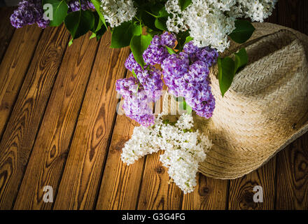 Still-life con un mazzo di lillà e un cappello di paglia, close-up Foto Stock