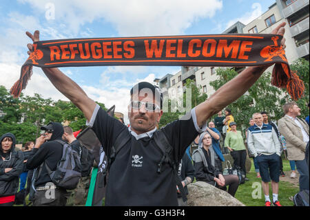 Londra, Regno Unito. Il 24 giugno 2016. Un anti-fascisti protester in Hamburg St Pauli shirt detiene una sciarpa con il messge "profughi" Benvenuto al rally in Altab Ali Park il giorno dopo che il Regno Unito ha votato per lasciare l'Unione europea contro il razzismo e per i diritti dei migranti e contro la violenza fascista. Essi dicono che la migrazione e gli immigrati sono stati aggrediti e scapegoated non solo da entrambi rimangono e lasciare le campagne ma dai principali partiti e media per più di venti anni, addensarsi l'odio insistendo gli immigrati sono un "problema".Peter Marshall / Alamy Live News Foto Stock