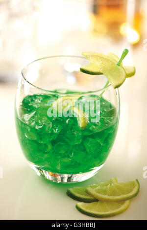 Cocktail di verde con ghiaccio tritato e fettine di lime in un bicchiere. Foto Stock