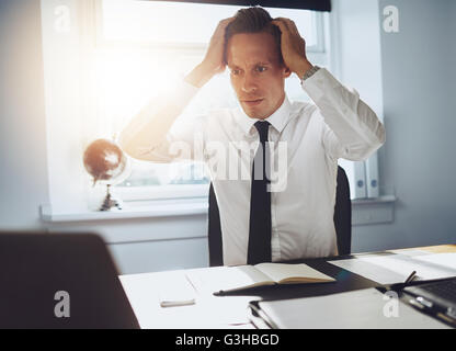 Frustrato uomo d affari guardando laptop tenendo le mani alla testa in frustrazione Foto Stock
