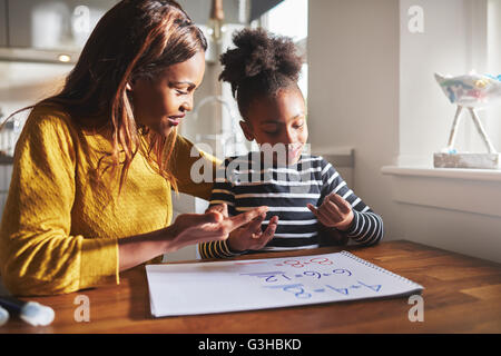 Nero a mamma e bambino facendo i compiti in cucina Foto Stock