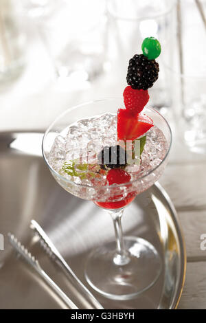 Cocktail Mojito con il ghiaccio tritato, rhum, zucchero e calce. Guarnita con frutta su uno spiedino. Foto Stock