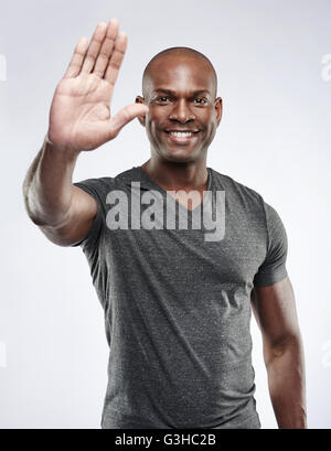 Unico bello athletic uomo sorridente azienda palm per i messaggi di saluto, di riconoscimento, di arresto o di timeout Foto Stock