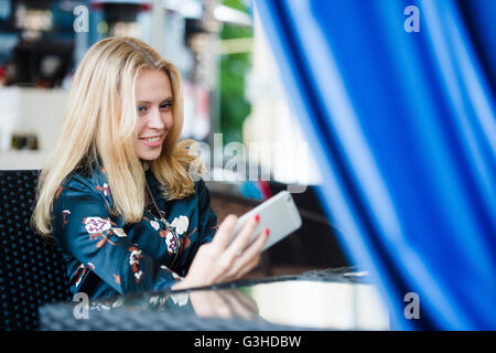 Giovane donna che fa autoritratto usando smartphone. ragazza rendendo selfie. donna in cafe. donna da soli. autoritratto al cafe' all'aperto. sorriso. smilimg. gadget. Self Portrait. coffe break. tempo di caffè Foto Stock