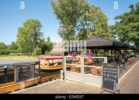 Giethoorn, Paesi Bassi. Il ristorante 't Achterhuus terrazza con passaggio di canal tour in barca. Sign in cinese per turisti cinesi. Foto Stock