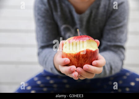 Kid mani tenendo un rosso morso apple, una mela al giorno mantenere il medico di distanza, il concetto di salute Foto Stock