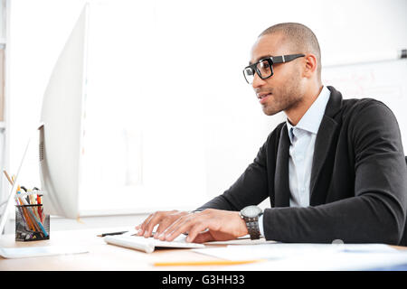 Smart giovane impreditore guardando i computer in ufficio Foto Stock