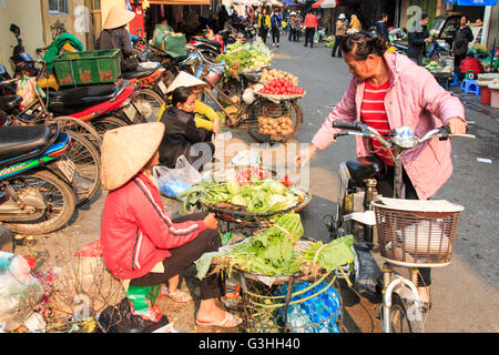 Hanoi, Vietnam: Febbraio 21, 2016: Womand la vendita di frutta e verdura in un mercato di strada di Hoàn Kiếm, il vecchio quartiere di hano Foto Stock