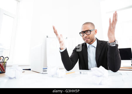 Gridando stanco uomo d affari con computer portatile alla sua scrivania in ufficio Foto Stock