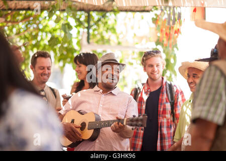 Commerciante di mercato la riproduzione di ukulele per intrattenere i turisti Foto Stock