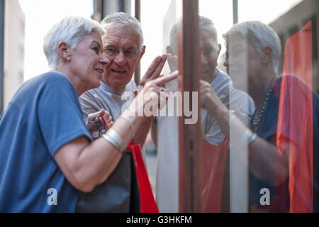 Coppia senior puntando alla città vetrina Foto Stock