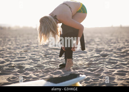 Giovani femmine surfer mettendo sul tipo di muta sulla Spiaggia di Venice, California, Stati Uniti d'America Foto Stock