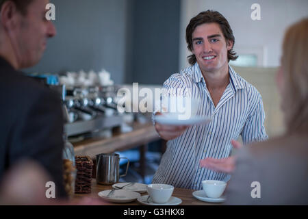Barista che serve caffè al cliente in cafe Foto Stock