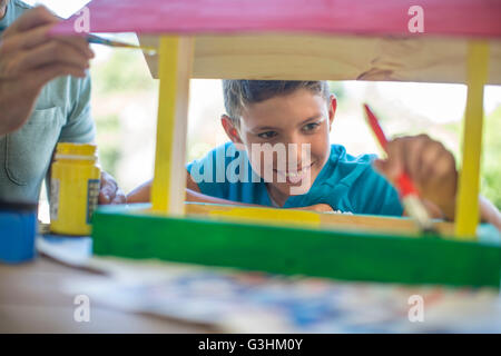 Padre e figlio fare artigianato insieme, pittura birdhouse in legno Foto Stock