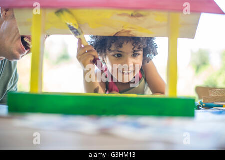 Padre e figlio fare artigianato insieme, pittura birdhouse in legno Foto Stock