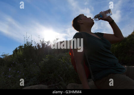 Silhouette di donna di bere acqua da bottiglie di plastica Foto Stock