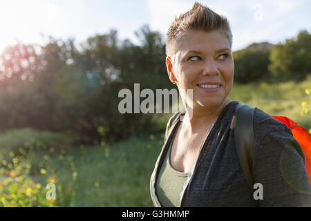 Donna escursionista che guarda lontano sulla spalla sorridente Foto Stock