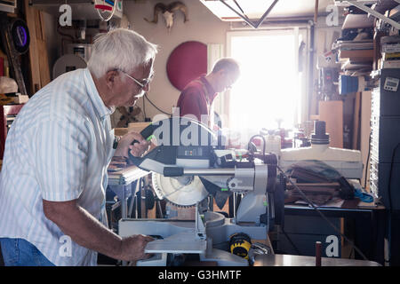 Senior uomo segatura su una sega circolare nel laboratorio di falegnameria Foto Stock