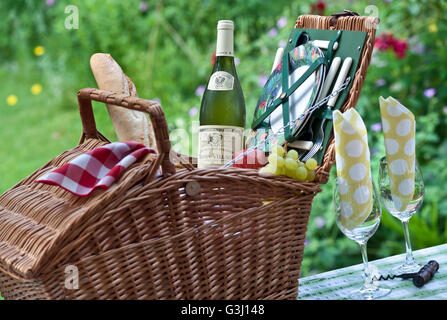 Giardino pic-nic bottiglia di vino bianco Borgogna Louis Jadot Macon villaggi e cesto da picnic in vimini in posizione soleggiata giardino di staycation floreale Foto Stock