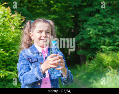 Ragazza in una camicia di denim tenendo una bottiglia di acqua all'aperto closeup Foto Stock