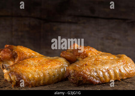 Due alette di pollo fritte sul pannello di legno Foto Stock