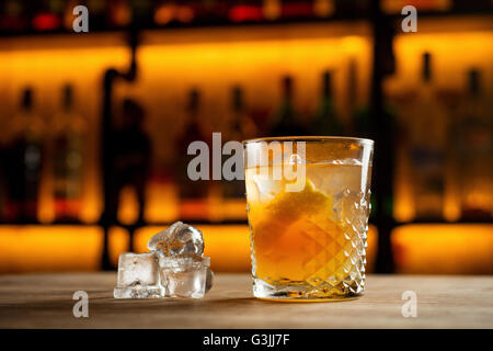 Bicchiere di deliziosi cocktail alcolico Lynchburg limonata con ghiaccio e una fettina di limone sulla tavola in bar o ristorante bellissimo bokeh in background Foto Stock