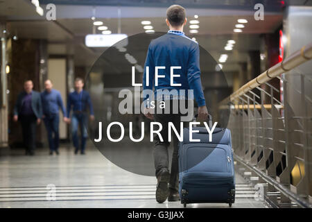 Giovane uomo tirando la valigia in aeroporto moderno terminale. Ragazzo in viaggio a piedi con il suo bagaglio mentre in attesa per il trasporto Foto Stock