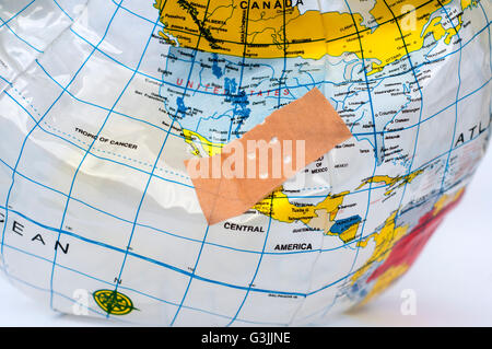 Cerotto su un globo di plastica che indica gli sforzi per fissare un pianeta morente in pericolo di essere distrutto dal cambiamento climatico Foto Stock