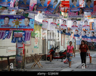 Manila, Filippine. 08 Maggio, 2016. I Filippini a piedi passato i banner della campagna dei candidati per le elezioni come si vede nei pressi di una scuola pubblica a Manila nelle Filippine alla vigilia del giorno delle elezioni. Cinquanta-quattro milioni di filippini gli elettori registrati sono voce ai centri di polling domani, 9 Maggio a votare per le elezioni presidenziali e vice presidential post, i successori di amministrazione corrente del presidente filippino Benigno Aquino III. Le elezioni generali includono anche i senatori e deputati del parlamento, e locali e provinciali di posizioni. © Marlo Cueto/Pacific Press/Alamy Live News Foto Stock