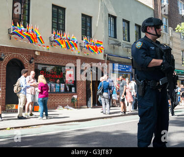 New York, Stati Uniti. 12 Giugno, 2016. Una lotta contro il terrorismo NYPD officer sorge in allerta al di fuori della Stonewall Inn. In mezzo a elevata sicurezza Newyorkesi mostrano la loro solidarietà con la comunità LGBT ponendo i fiori al di fuori della Stonewall Inn -- considerato un epicentro dei diritti dei gay movimento -- nel Greenwich Village di New York City, NY, Stati Uniti d'America in seguito alla ripresa di massa in corrispondenza dell'impulso nightclub a Orlando in Florida che ha lasciato 50 morti e decine di feriti. Credito: Albin Lohr-Jones/Pacific Press/Alamy Live News Foto Stock