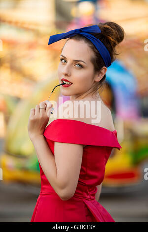 Ritratto di una giovane donna che indossa abito rosso in luna park Foto Stock