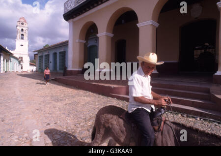 Cuba, Trinidad, uomo sulla schiena d'asino con torre campanaria in background Foto Stock