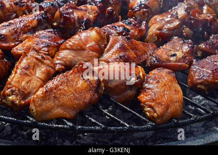 Bufali di pollo o salsa teriyaki ali cotta alla brace sul fumo barbecue grill rotondo, close up Foto Stock