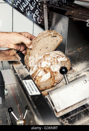 Baker con la pagnotta di pane affettato Foto Stock