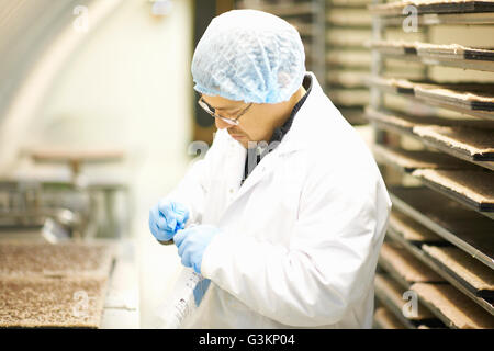 Vista laterale del Lavoratore che indossa hairnet e guanti in lattice raccolta di campioni in un sacchetto di plastica Foto Stock